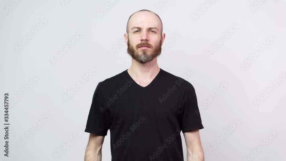 Portrait of calm bearded man looking at camera isolated over white background. Emotionless posing. Portrait of calm bearded man looking at camera isolated over white background. Emotionless posing.