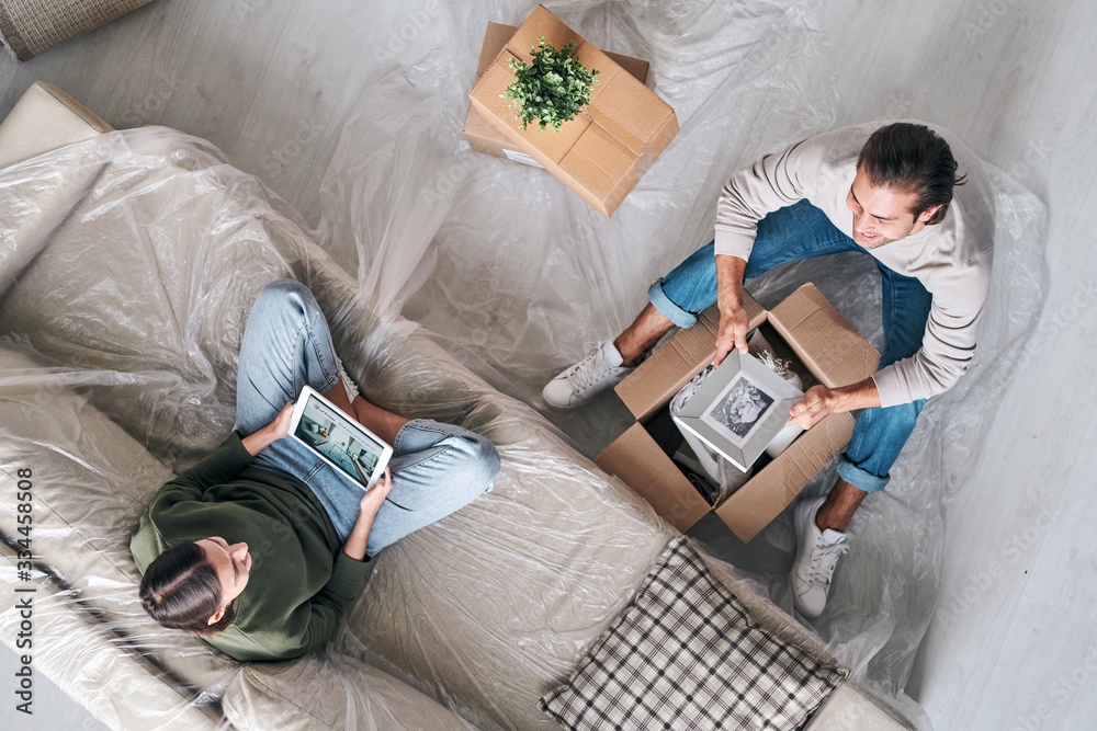Obraz premium Affectionate couple discussing their plans for the future while unpacking boxes