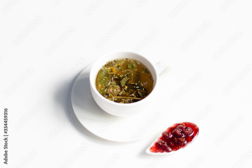 Cup of brewed herbal tea and raspberry jam on white background Cup of brewed herbal tea and raspberry jam on white background