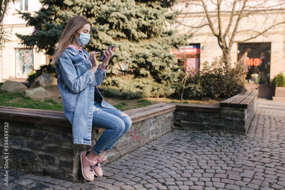 Girl in mask. Coronavirus theme. Women in the city, during quarantine. Alone in the city. Female use phone Girl in mask. Coronavirus theme. Women in the city, during quarantine. Alone in the city. Female use phone