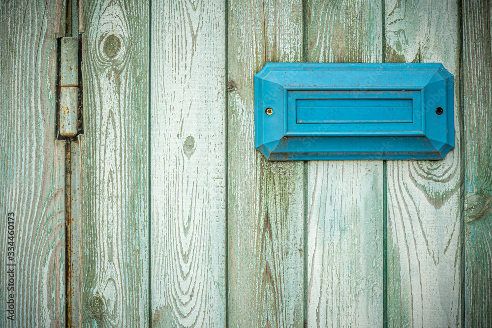Blue rectangular address plate / mailbox on an old shabby turquoise fence