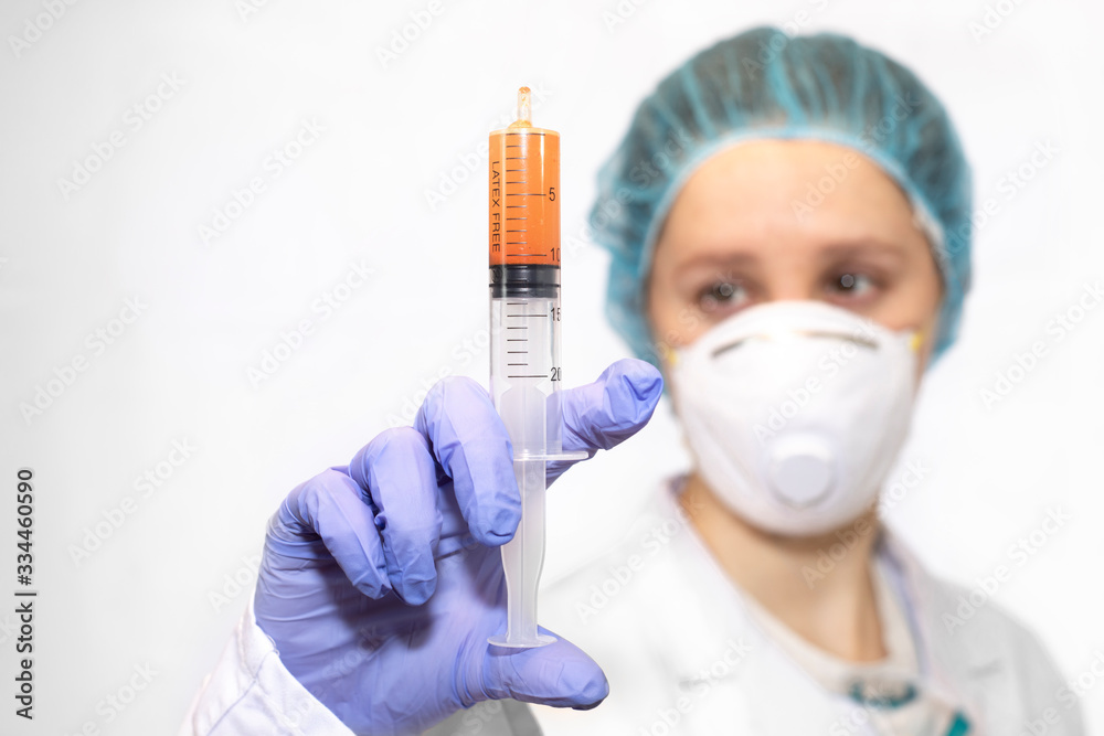 nurse or doctor with her protective equipment on with a syringe in her hand nurse or doctor with her protective equipment on with a syringe in her hand