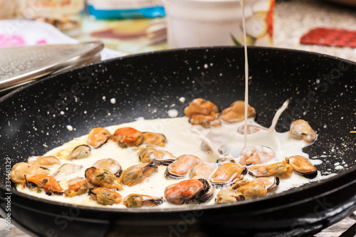 Preparation of pan with mussels in white cream sauce.
