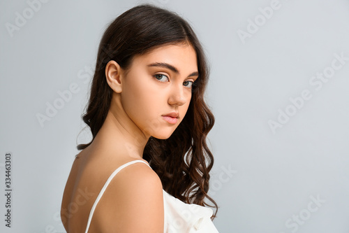 Young woman with beautiful curly hair on grey background