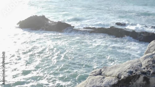 Moving down from the view above the ocean into waves crashing between rocks.