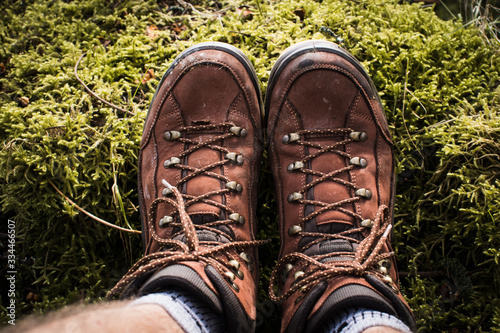 Detalle de botas de senderismo marrones sobre musgo verde photo