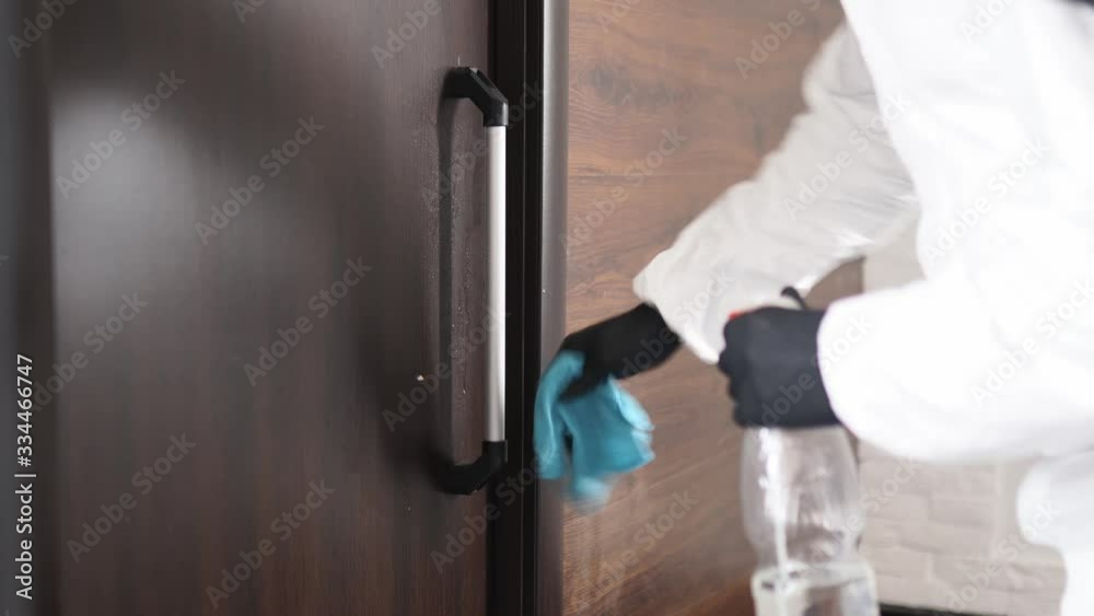 Close view of hand in medical glove using antibacterial sprayer, wipe for disinfecting door knob. Disinfection and cleaning of doorhandles. Germs, bacteria, Covid-19, SARS, Coronavirus pandemic. Close view of hand in medical glove using antibacterial sprayer, wipe for disinfecting door knob. Disinfection and cleaning of doorhandles. Germs, bacteria, Covid-19, SARS, Coronavirus pandemic.