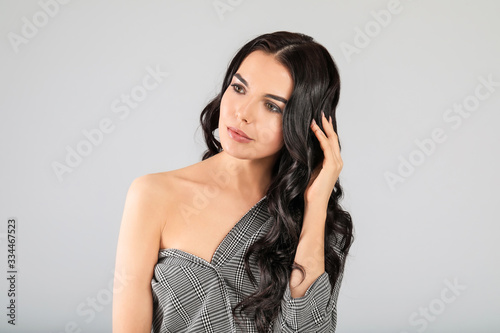 Young woman with beautiful healthy hair on grey background