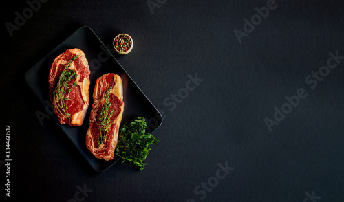 Two raw Rib eye japanese steaks with spices on a black background