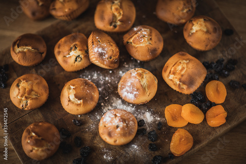 Freshly baked muffins with raisins and dried apricots, shot on a dark background. Background for baking and cooking.