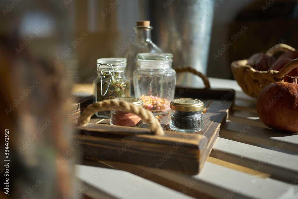 spices in glass jars are placed on a wooden tray. light from the window spices in glass jars are placed on a wooden tray. light from the window