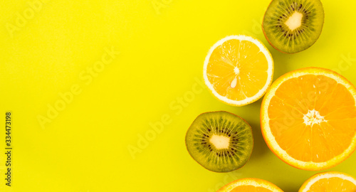 Fruit frame. Colorful fresh citrus fruits on a light green background. Orange  tangerine  lemon and kiwi are cut in half. Flat lay  top view  copy space.