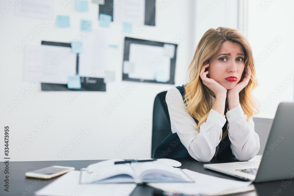 young blond beautiful woman manager works in her modern office, holding her hands near face looks helpless and tired facing deadline, multitasking, work concept