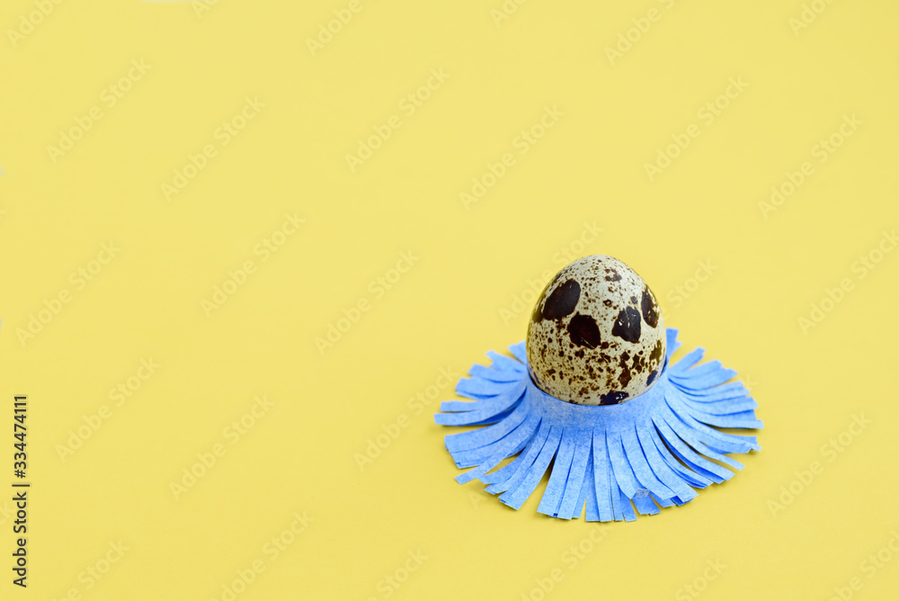 Decorated quail egg on a yellow background. Children's creativity, crafts
