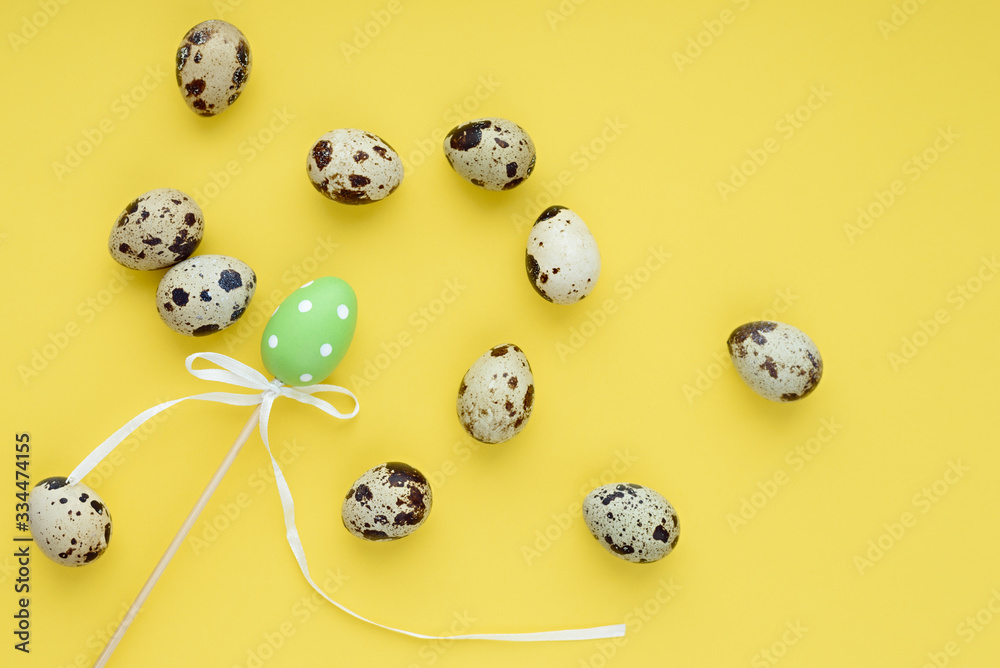 A chaotic pattern of Easter eggs on a yellow background. Happy easter banner. One decorative egg on a stick among small quail eggs