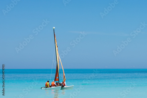 a colorful and beautiful catamaran sails the turquoise blue waters with tourists in the clear waters of cuba