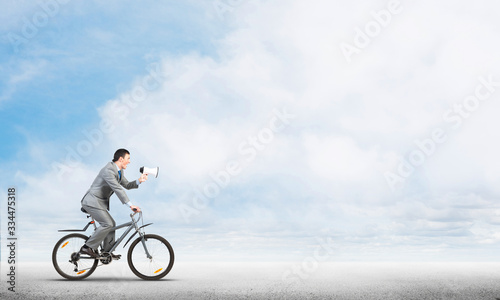 Businessman with megaphone on bike