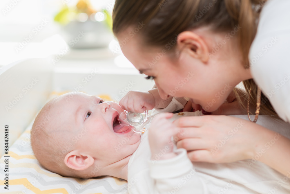 Beautiful smiling mother and her baby are playing at home. Beautiful smiling mother and her baby are playing at home.