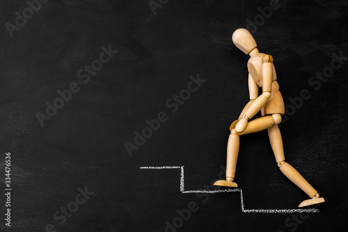 Obraz na płótnie Wooden business man climbs the steps drawn on a chalk board w salonie
