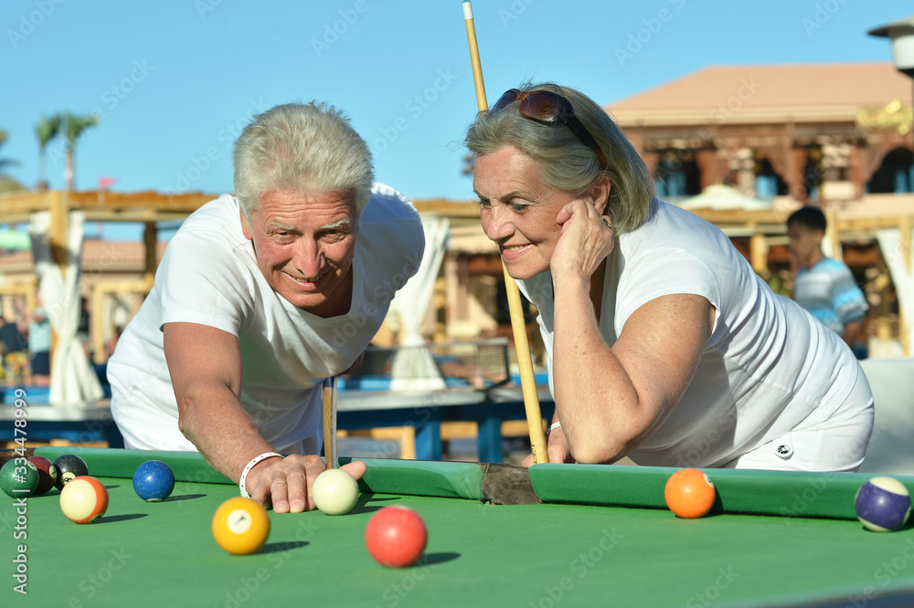 Fototapeta premium Portrait of smiling senior couple playing billiard together