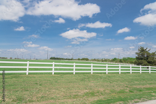 Long wooden white fence to horizontal line in cloud blue sky at farmland in Ennis, Texas, USA