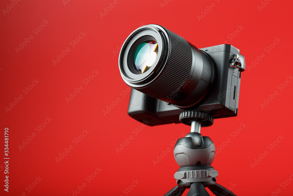 Professional camera on a tripod, on a red background. Record videos and photos for your blog, reportage Professional camera on a tripod, on a red background. Record videos and photos for your blog, reportage