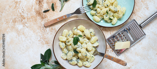 Italian homemade gnocchi with butter, cheese and sage served in two plates on a light marble table. Italian food. Copy space. Banner. Flat lay photo