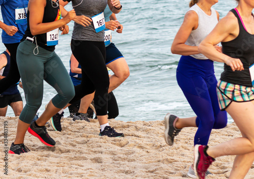 Side view of runners running on the sand close to the ocean