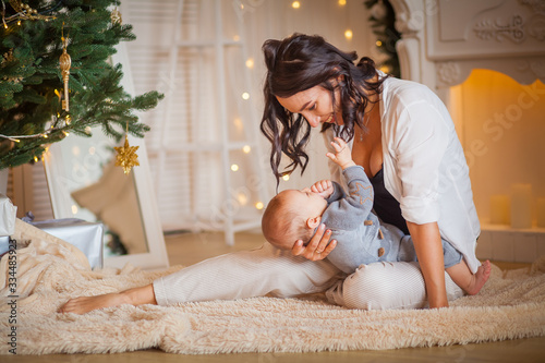 mother with her newborn son near the Christmas tree