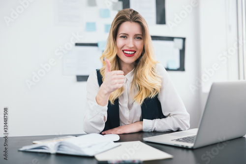 young beautiful businesswoman manager with red lipstick works in her modern office, shows like sign, body language concept