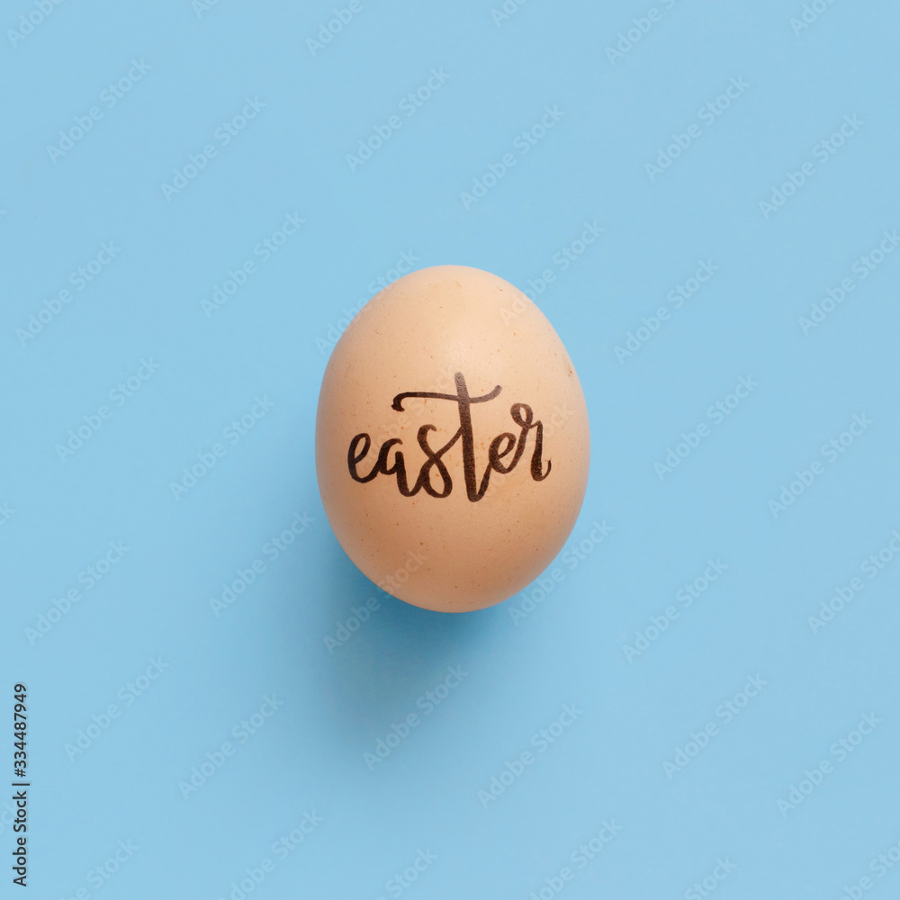 Egg with inscription EASTER over light blue background Egg with inscription EASTER over light blue background