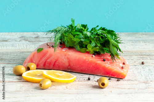 Sliced piece of salmon, lemon and greens on the table photo