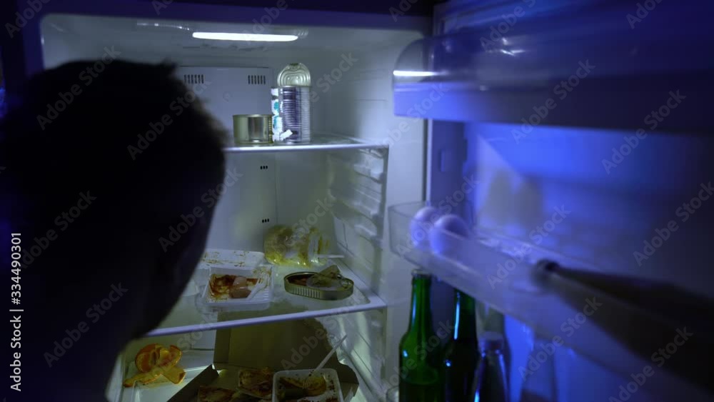 A man during self-isolation is looking for food in the refrigerator. Leftover food in the refrigerator during quarantine. The ban on leaving the house on the street. Stay at home. Coronavirus.COVID-19 A man during self-isolation is looking for food in the refrigerator. Leftover food in the refrigerator during quarantine. The ban on leaving the house on the street. Stay at home. Coronavirus.COVID-19