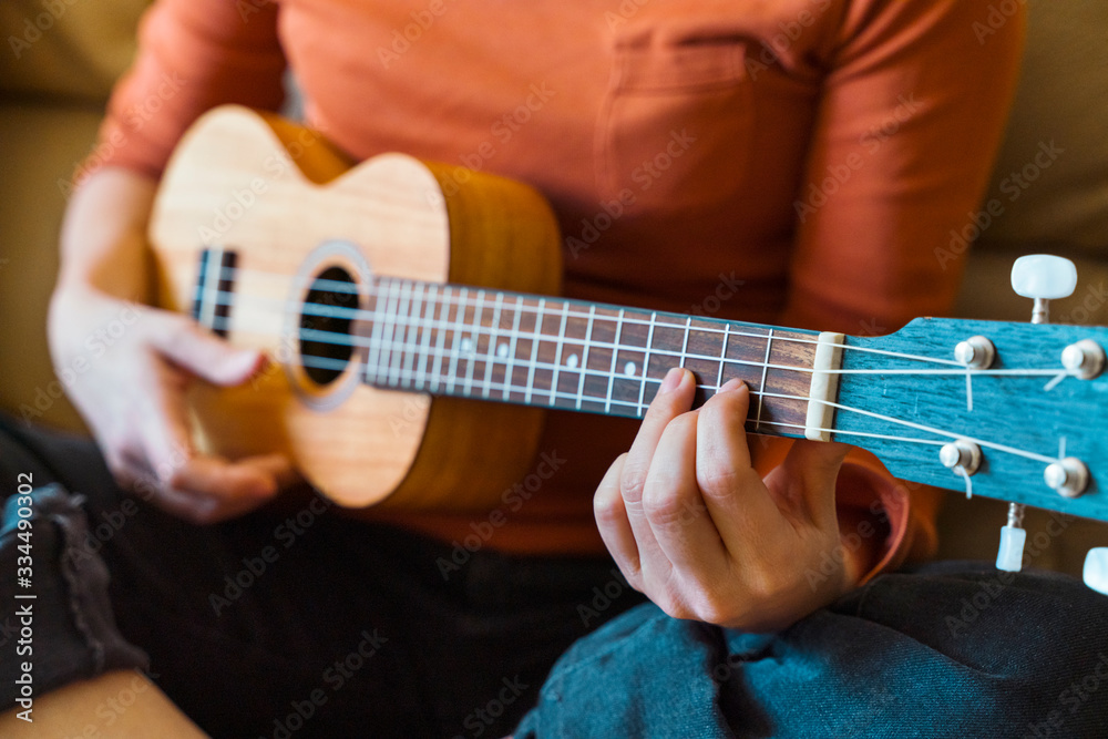 Detail of unrecognizable teacher and student of music lessons. Female professor close up explaining instructions of accurate ukelele chords position on guitar neck with bridge. Spanish guitar concept.