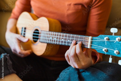 Detail of unrecognizable teacher and student of music lessons. Female professor close up explaining instructions of accurate ukelele chords position on guitar neck with bridge. Spanish guitar concept.