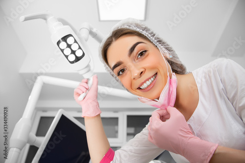 The patient's first-person view at the examination by the dentist lies in the dental chair. Doctor Dental surgeon examines an oral cavity with the help of somatological tools photo