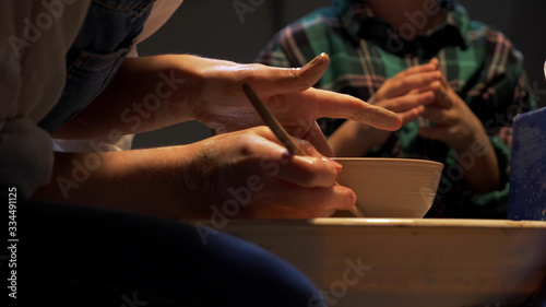 Woman sculpts a plate on a pottery wheel