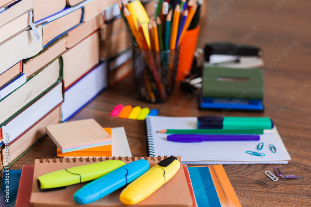 School stationery accessories - notebook, copybook stack with plastic holder pencils, pens, markers, paper clips, stickers, notepads, sharpener with stack of books education concept background. School stationery accessories - notebook, copybook stack with plastic holder pencils, pens, markers, paper clips, stickers, notepads, sharpener with stack of books education concept background.