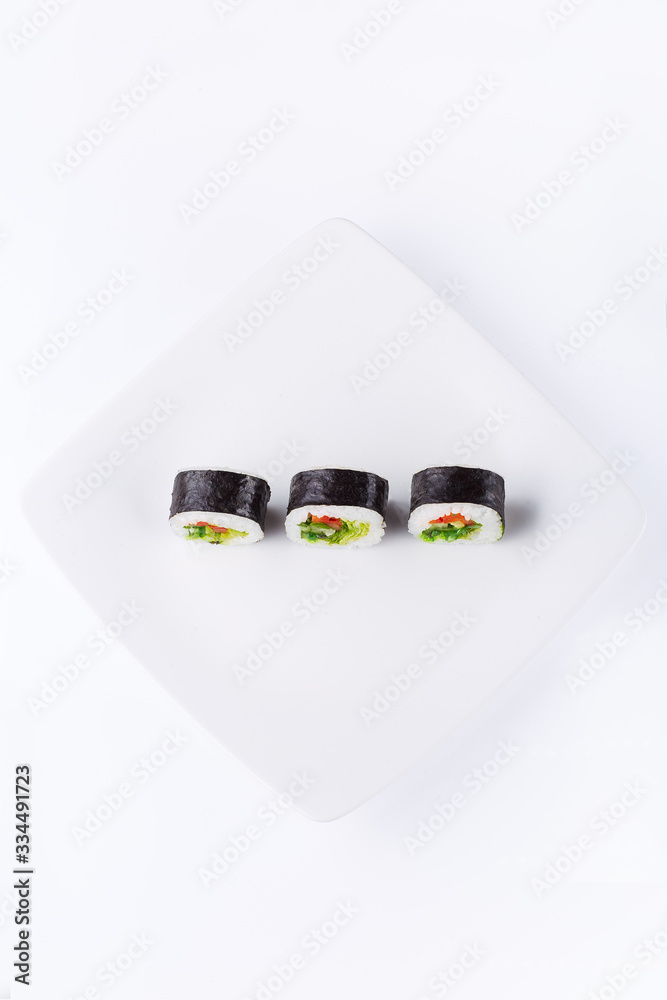 Three sushi on a white square plate on a light background. Top view Three sushi on a white square plate on a light background. Top view