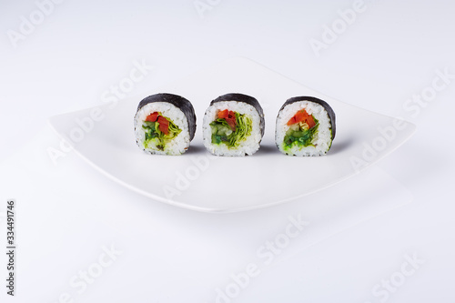 Three sushi on a white square plate on a light background. 