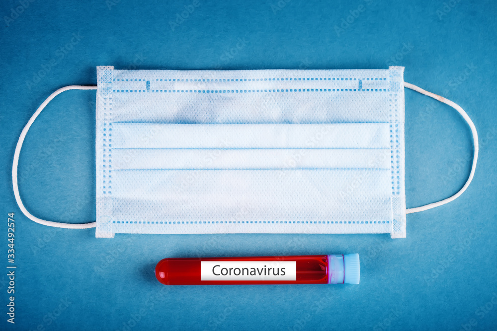 Medical mask and a test tube with a blood test on table. Coronavirus Pandemic. Horizontal. Medical mask and a test tube with a blood test on table. Coronavirus Pandemic. Horizontal.