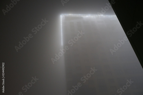 Skyscraper house in the fog at night. luminous peak.