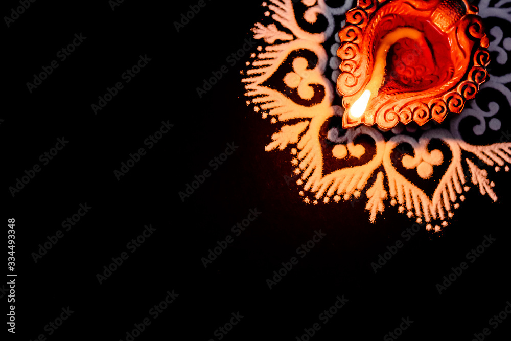 cropped close up terracotta lamp in the up right corner and beautiful rangoli on black background with copy space. diwali concept cropped close up terracotta lamp in the up right corner and beautiful rangoli on black background with copy space. diwali concept