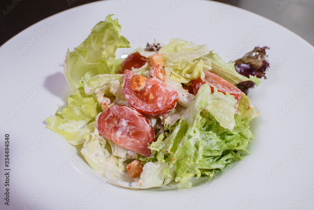 Delicious fresh caesar salad on a large white plate. Delicious fresh caesar salad on a large white plate.