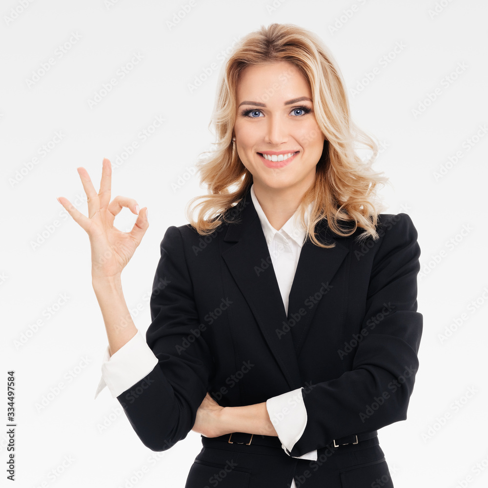 Happy confident businesswoman showing okay gesture, on grey background. Caucasian blond model in business presentation concept. Square composition. Happy confident businesswoman showing okay gesture, on grey background. Caucasian blond model in business presentation concept. Square composition.
