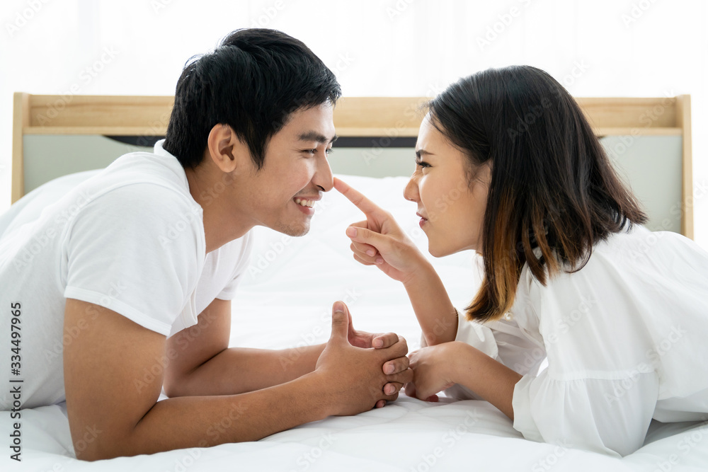Funny and romantic Asian couple' portrait in bedroom with natural light from window, concept of relationship between husband and wife and being a family. Funny and romantic Asian couple' portrait in bedroom with natural light from window, concept of relationship between husband and wife and being a family.