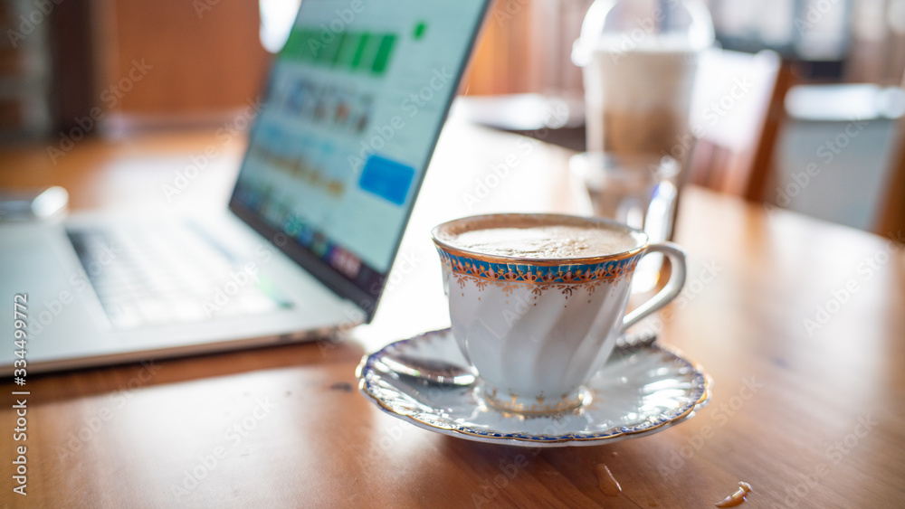 Hot aroma cappuccino coffee cup on wooden table work from home with laptop Hot aroma cappuccino coffee cup on wooden table work from home with laptop