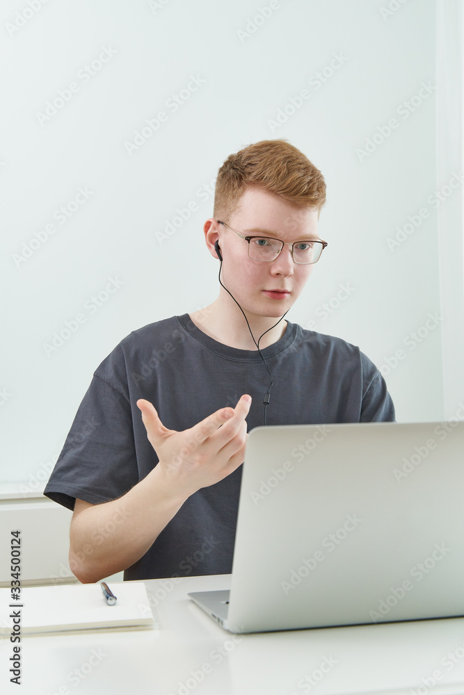 Distance learning or working. Quarantine, self-isolation, social phobia. Young boy speaking on online training, Distance learning or working. Quarantine, self-isolation, social phobia. Young boy speaking on online training,