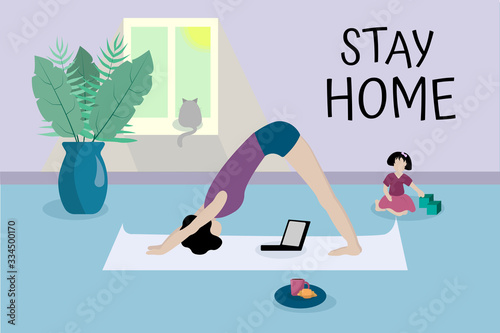 young girl practices yoga in front of laptop in her apartment. Text Stay home. Against background of child, cat, vase with tropical plants. Home office, freelancer