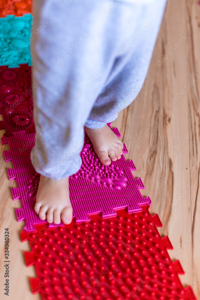 Orthopedic foot mat for child gymnastic. Small children with a flat-bottomed stomach goes barefoot on an orthopedic foot mat for the appointment of an orthopedist.